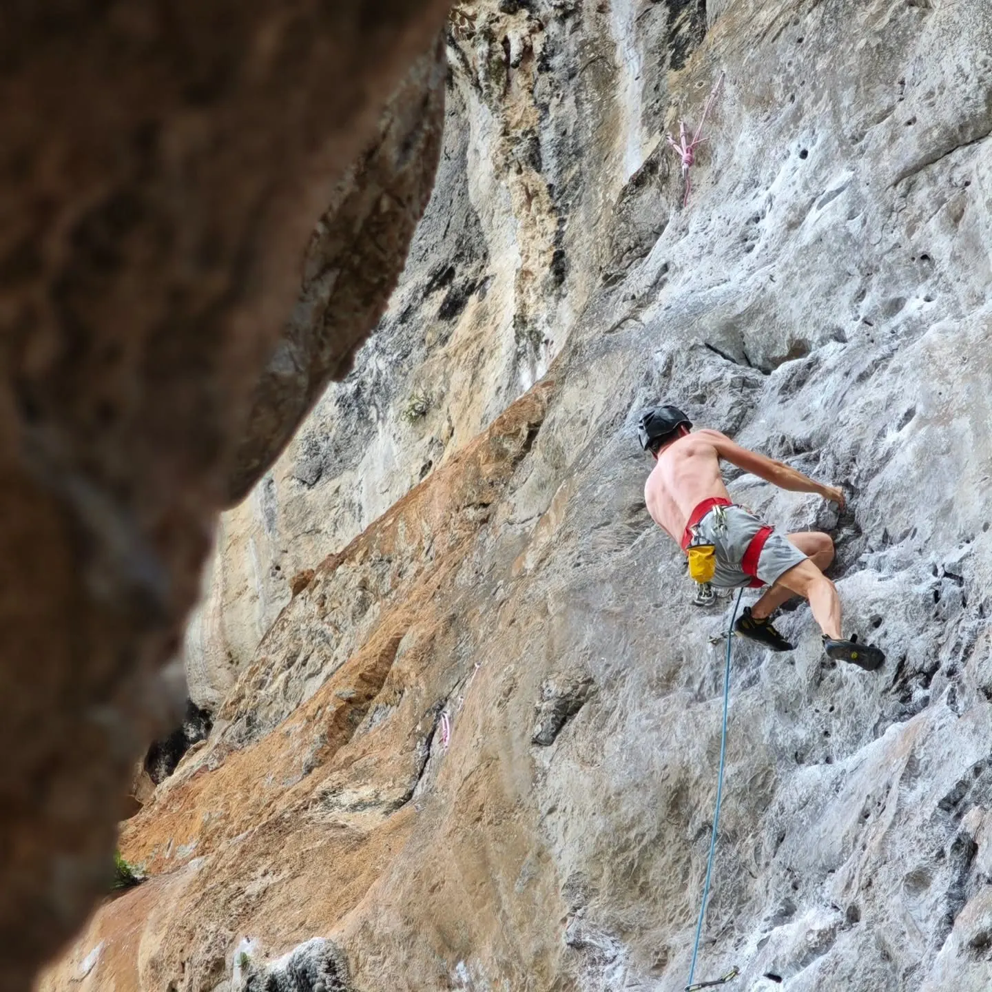 A climber high on grey limestone at Railay
