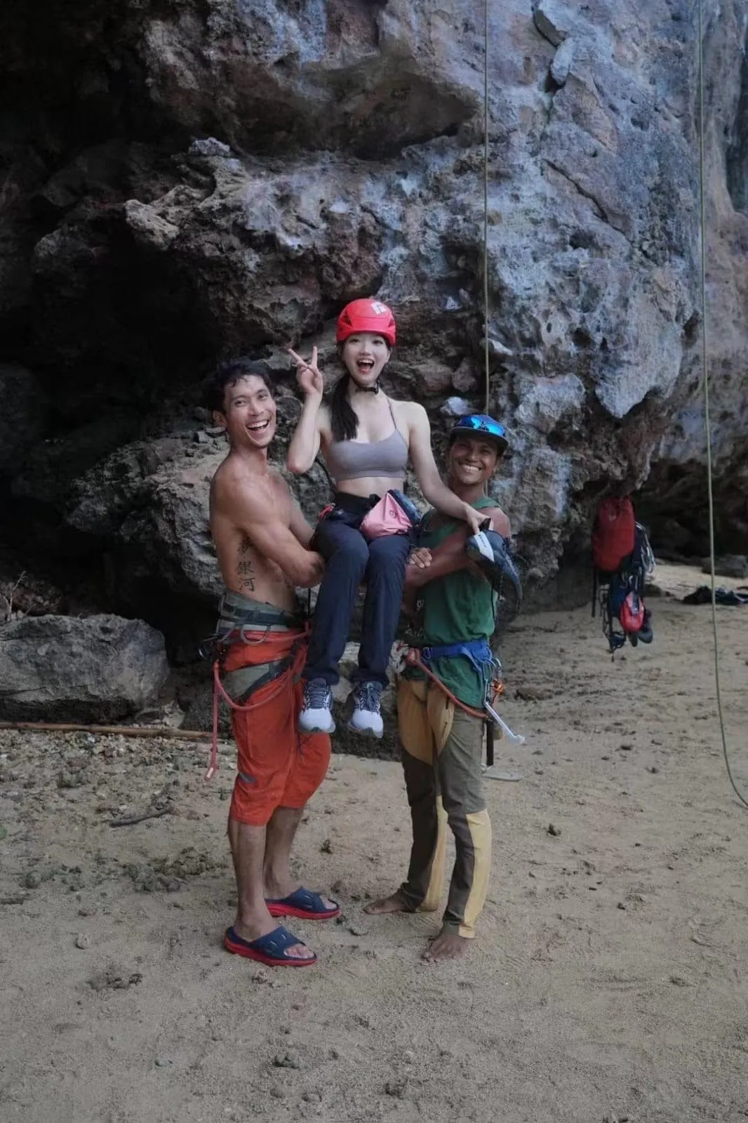 Two instructors laughing with a young guest at the foot of the cliff