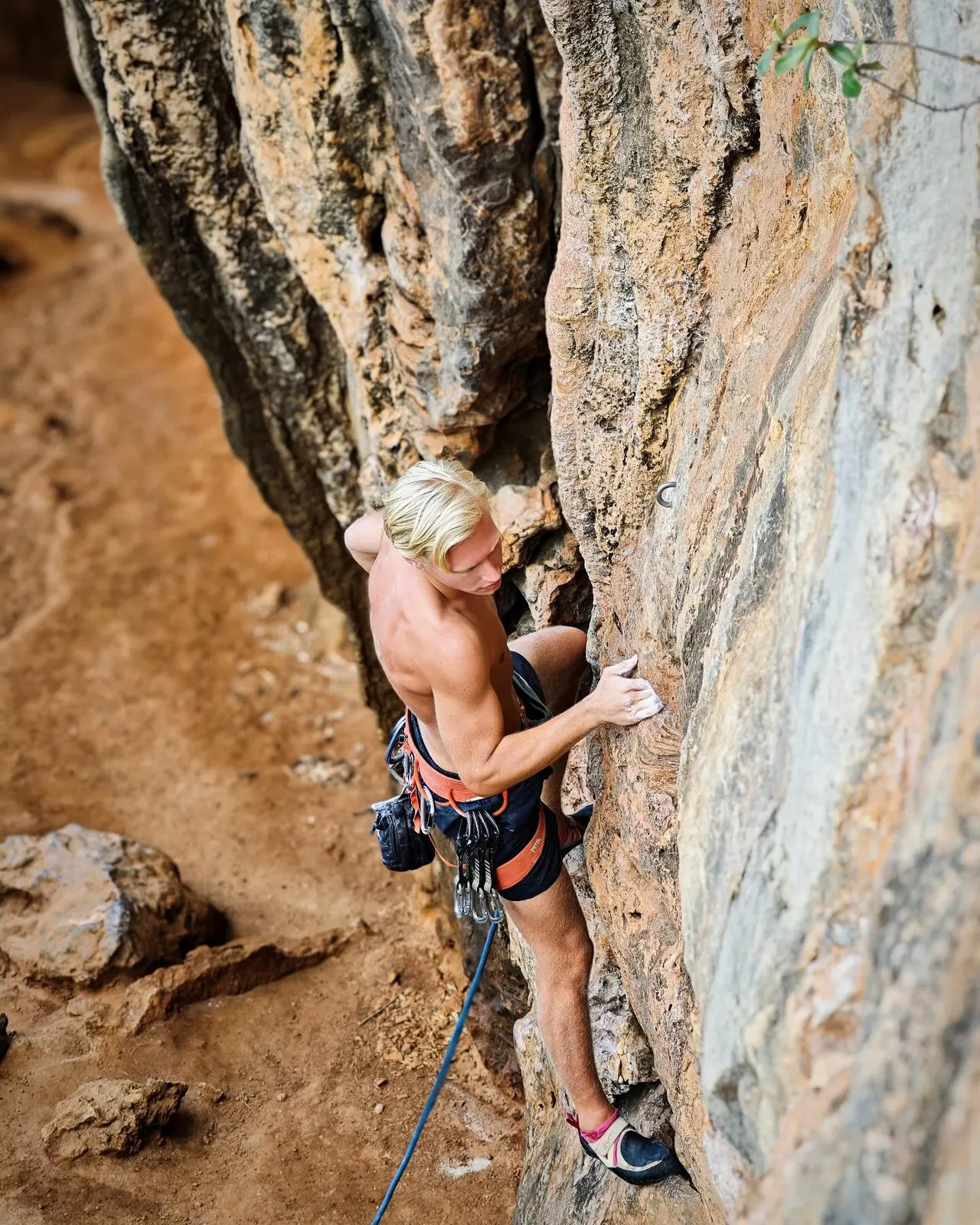 A climber leading up an orange limestone wall