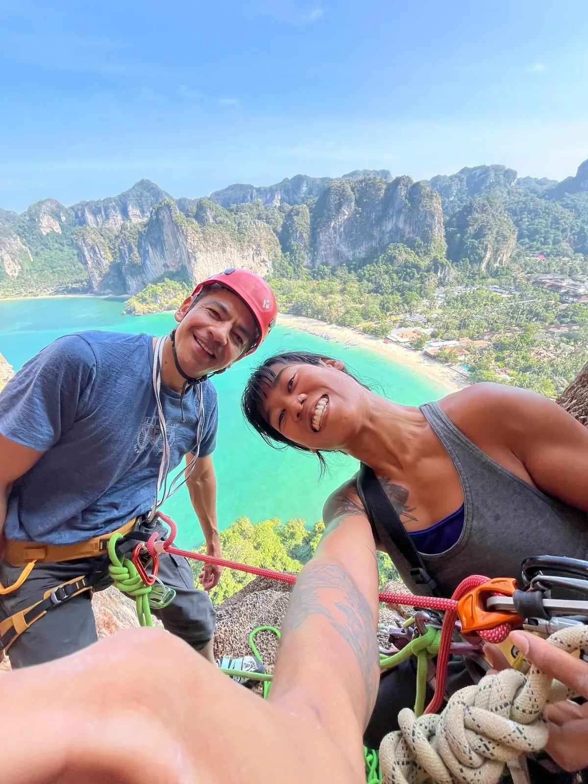 Two climbers on a ledge high above Railay bay