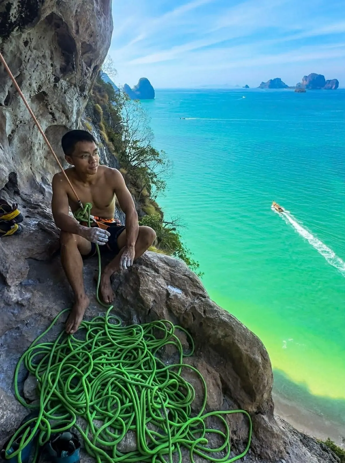 An instructor coiling rope on a ledge above turquoise water